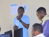 Nabasa Jonathan speaking in a classroom, wearing a bright blue collared shirt