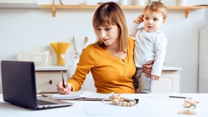 working mum at desk holding toddler