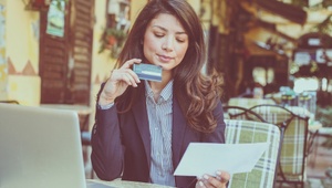 business woman sat outside cafe with laptop and credit card