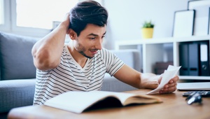man scratching head looking at paperwork