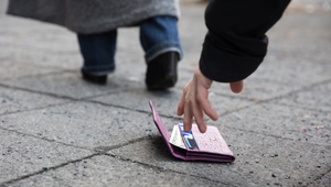 man picking up purse dropped on the path
