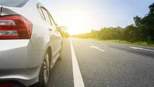 silver car driving down sunny road