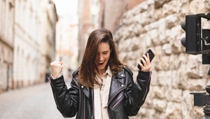 woman making the winner gesture while holding her mobile phone