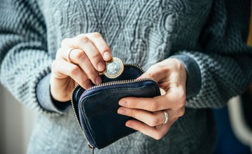 A lady putting a coin she's saved into her purse