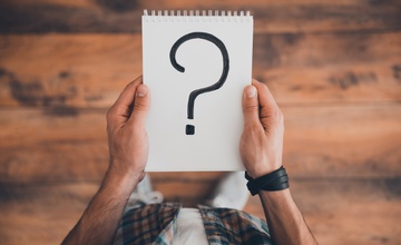 Someone looking at a pad with a question mark on it representing their credit score