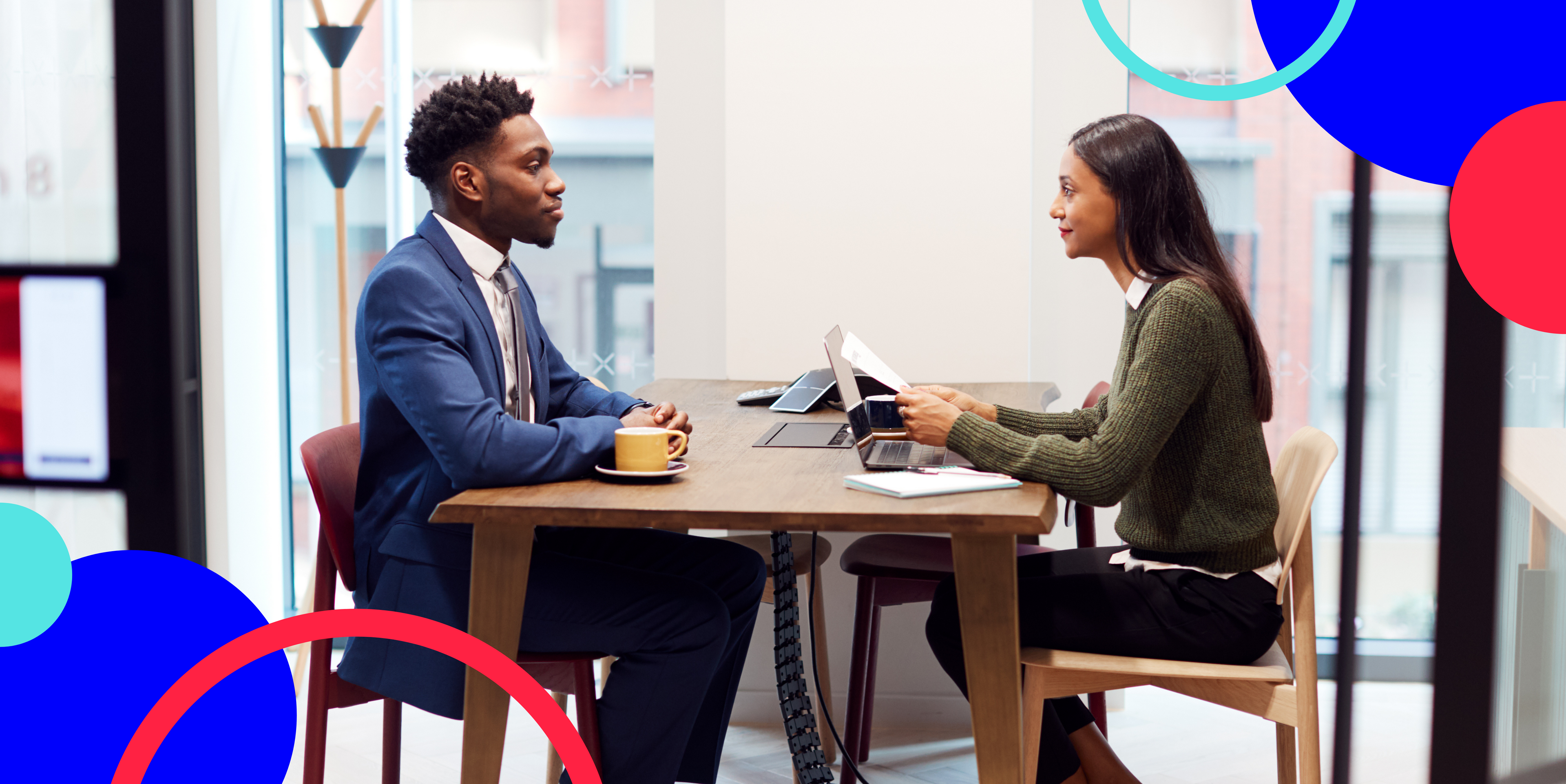 young black man and ethnic woman sitting at a table together in an interview