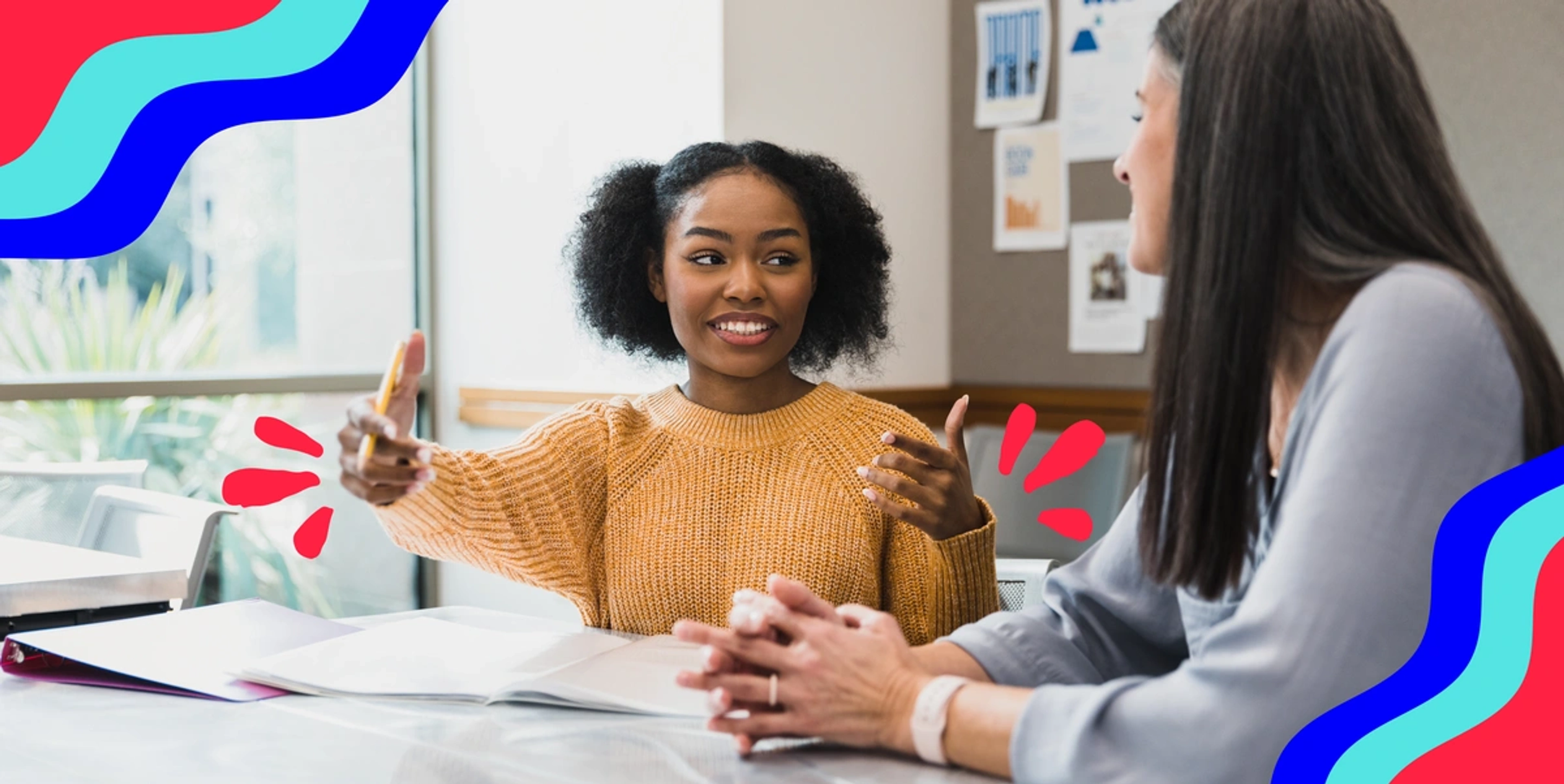 two women sitting in an office talking, smiling and looking engaged