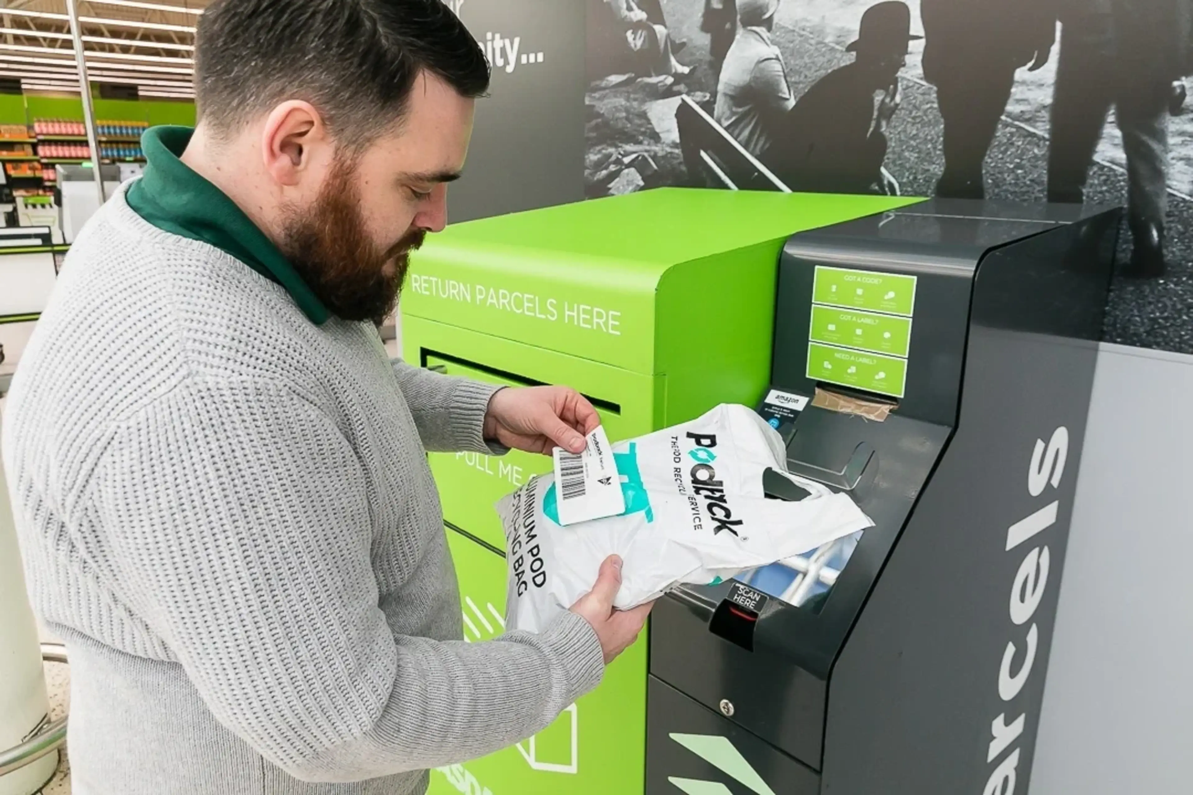 A man stands by a parcel drop box and sticks a returns label on a white Podback bag.