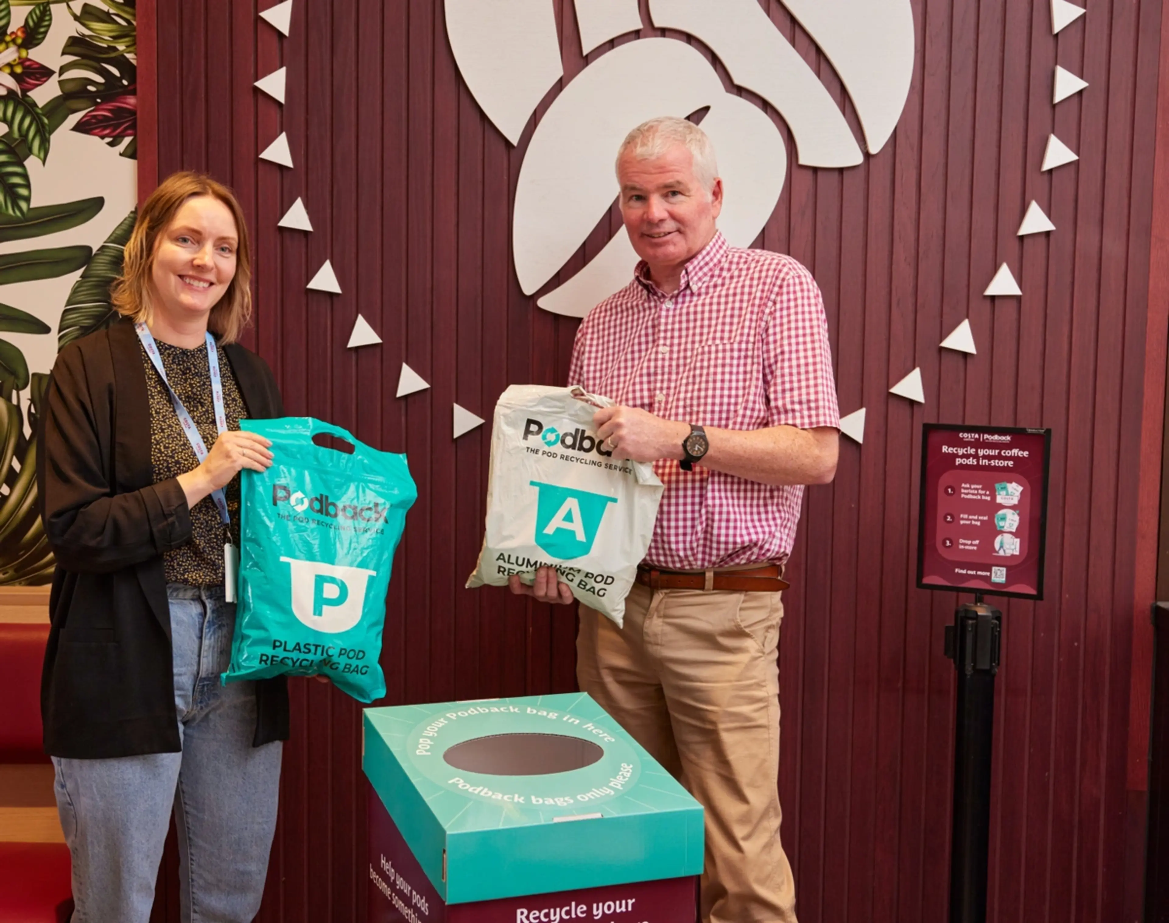 Two people in a coffee shop dropping their Podback coffee pod recycling bags into a recycling box.