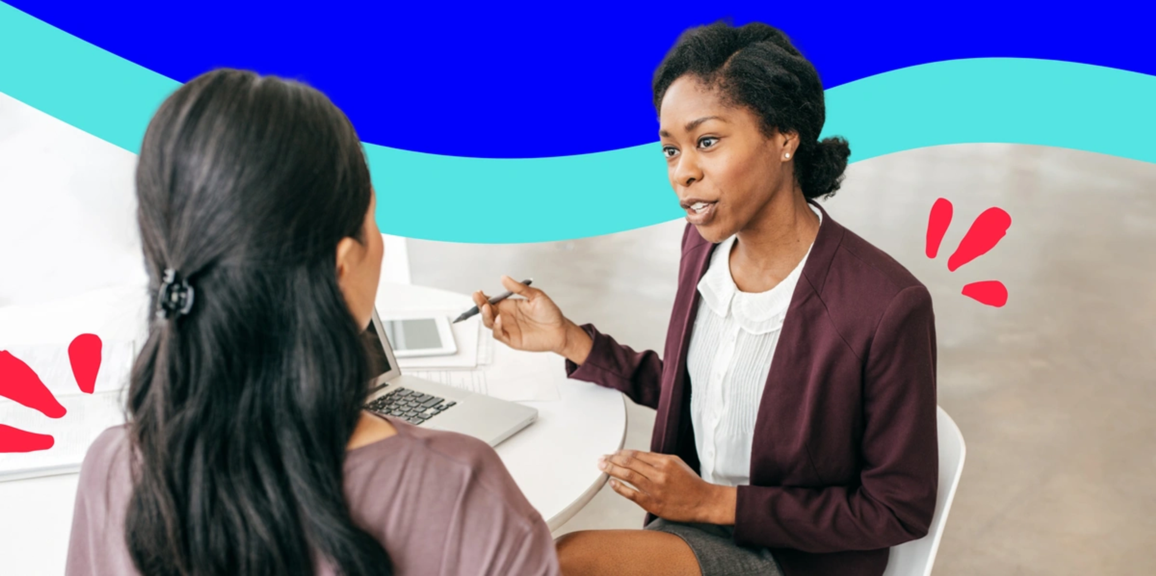 two women sitting and talking in front of a laptop looking serious