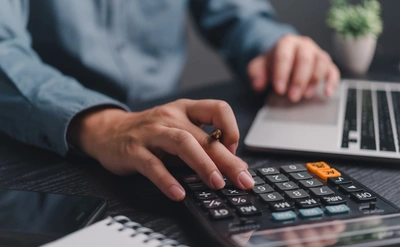 close up of a man on his laptop and using a calculator
