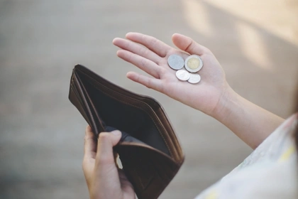 woman looking at coins left in purse