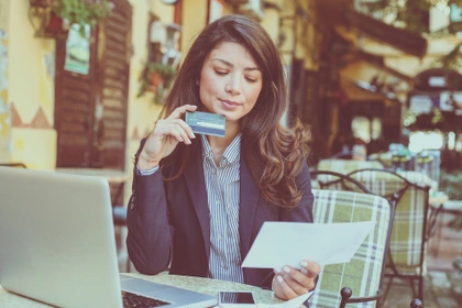 business woman sat outside cafe with laptop and credit card