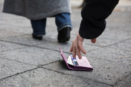 man picking up purse dropped on the path