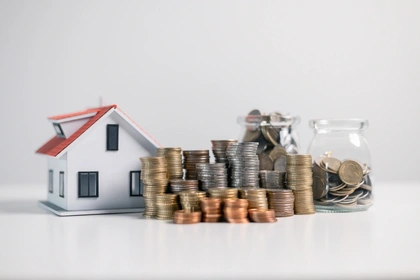 Toy house with money stacked next to it