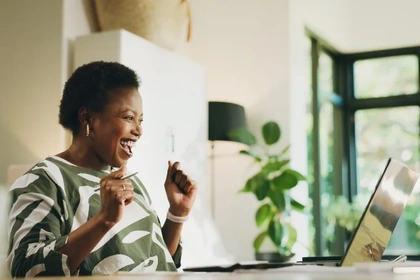 Woman at a computer celebrating an increase in her credit score 