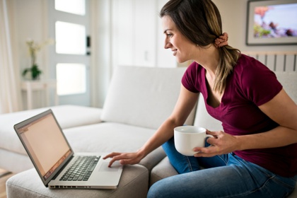 Woman on laptop with cup of coffee