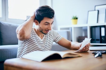 man scratching head looking at paperwork