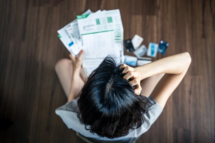 Woman scratching her head whilst looking at a pile of finance statements