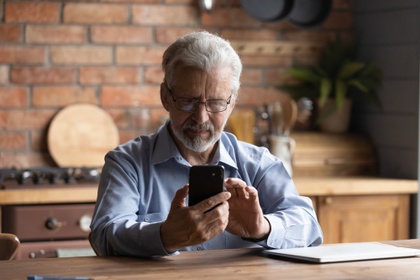 Man doing sums on a phone whilst looking at paperwork