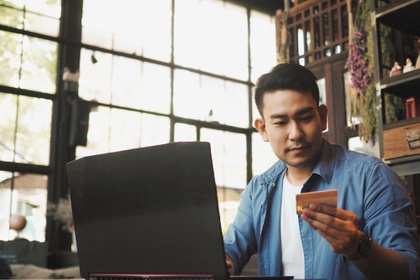Man on his laptop, looking at credit card