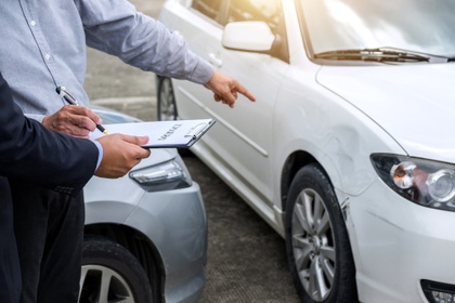 Man pointing out a dint in his car and having it assessed for insurance claim