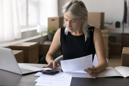 Woman on calculator checking figures alongside paperwork