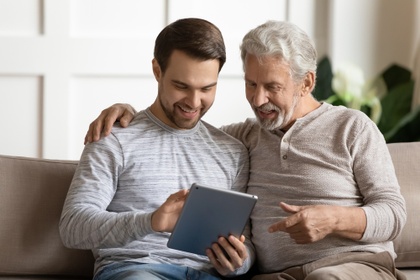 Father and son on sofa looking at tablet computer