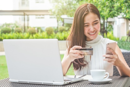 Young woman on her laptop and mobile, using a credit card