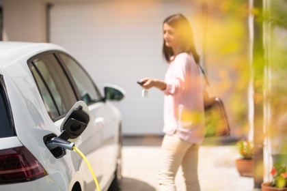 Woman standing next to her electric car whilst it charges