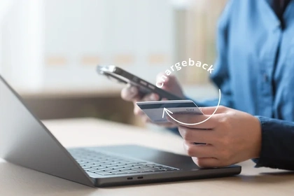 Close up of a man at his laptop holding a credit card in one hand and a mobile phone in the other