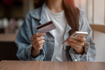 Close up of a woman holding a mobile phone and a credit card