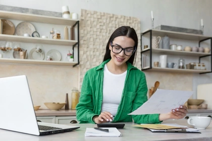 Woman looking at papers in front of laptop