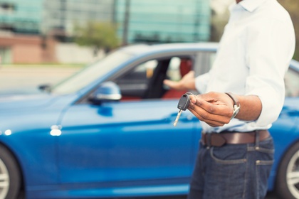 man holding keys outside a car