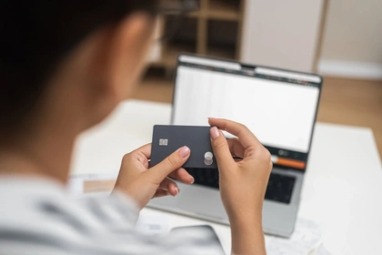 Woman holding a credit card with the image of a laptop in the background