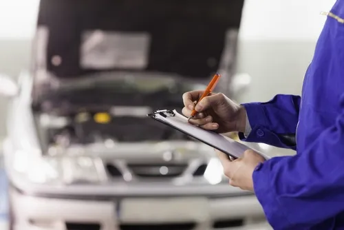 Mechanic with clipboard checking car at a garage 