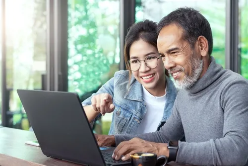 Father and daughter at a laptop looking at loans
