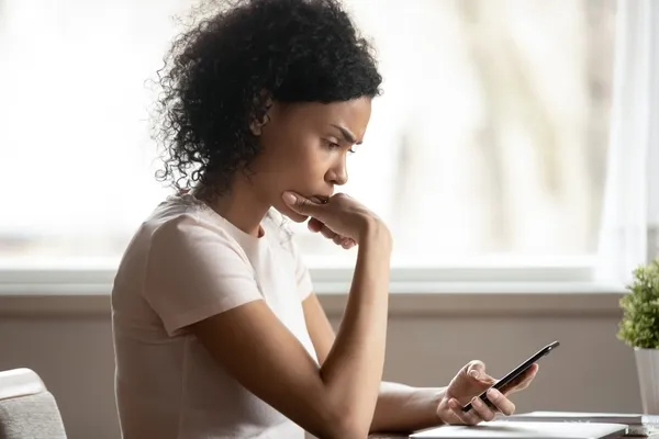 worried woman looking at mobile phone