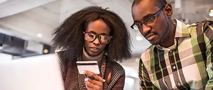 A couple looking at a credit card while using a computer