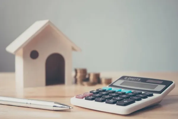 A calculator on a table with a pen and coins