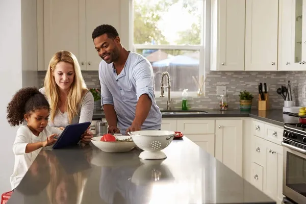A family looking at a tablet on a kitchen counter