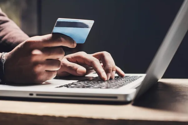 Person holding a credit card while browsing on a laptop