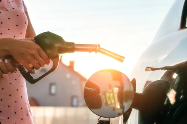 Lady in pink spotted dress refuelling her car at sunset