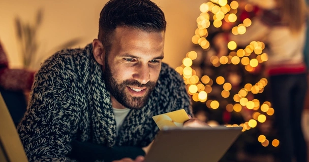 Man online shopping with a Christmas jumper on