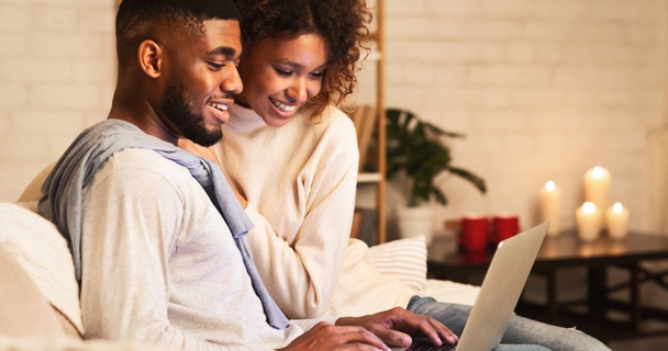 Happy Black couple using laptop