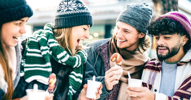 Group of friends talking and drinking coffee outdoors during winter