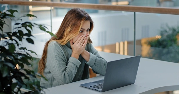 woman looking shocked on laptop