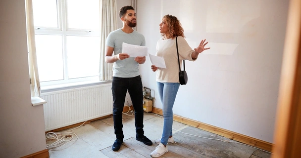 Couple looking at a house survey in a room to be renovated