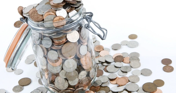 Mason jar with a variety of British coins on a white background