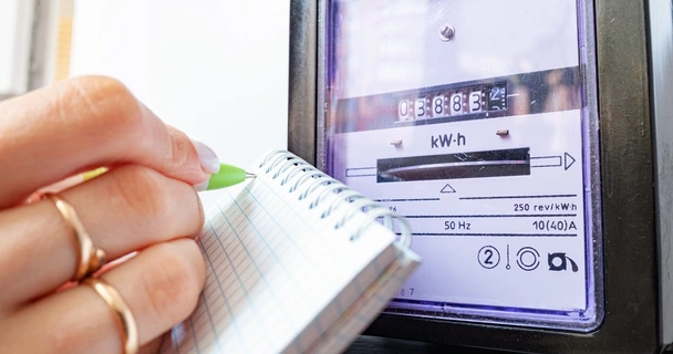 Close up of energy meter with a woman writing on a note pad